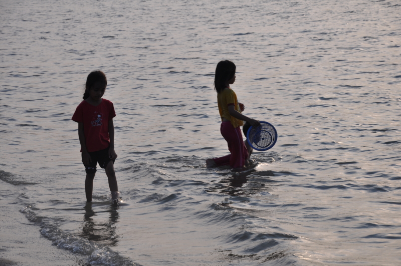 Cesta na Langkawi: siluety detí v mori, jedno z nich nesie košík
