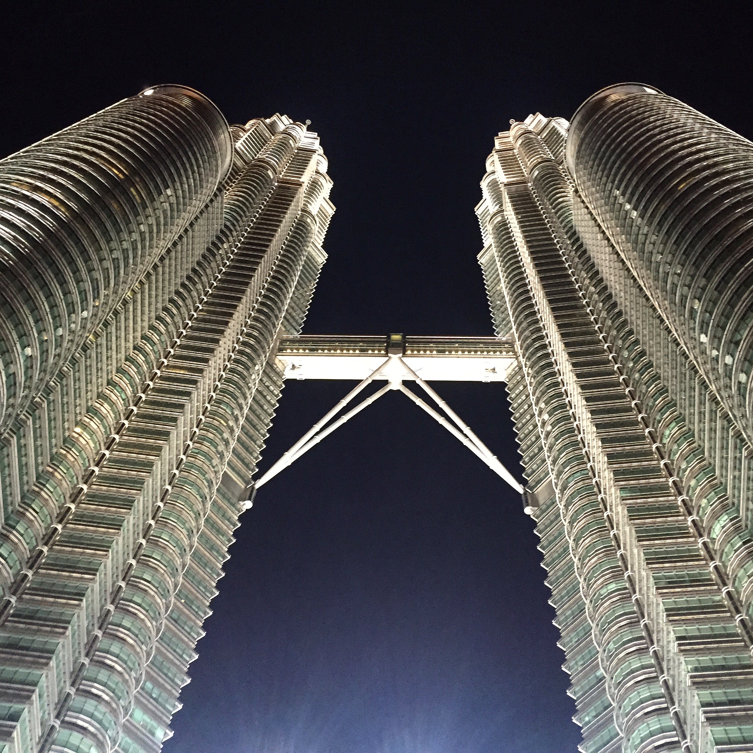 Pohľad na nasvietené dvojičky Petronas Towers zospodu počas noci