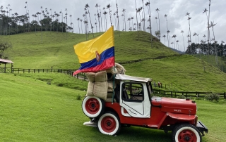 Valle de Cocora - červené staré auto s kolumbijskou vlajkou a v pozadí štíhle a vysoké voskové palmy na kopci
